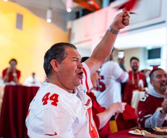 a man cheers with an arm raised in the air during the 49ers watch party