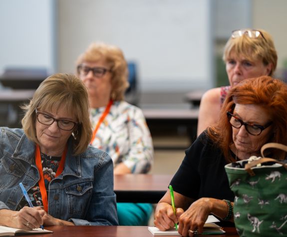Two women taking notes for a olli class