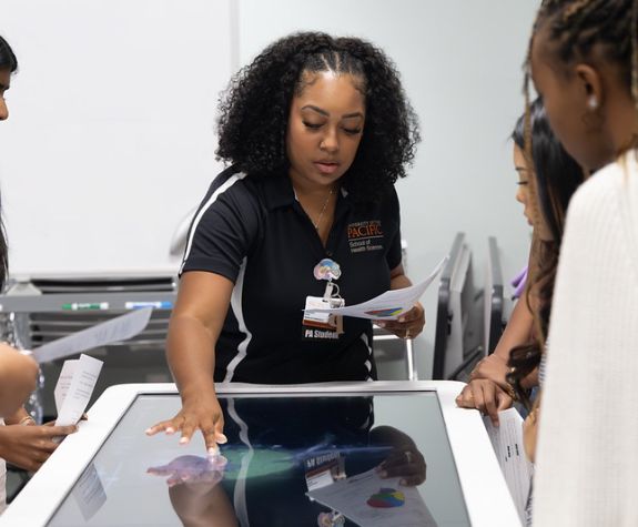 A PA student is shown using a digital anatomy table.
