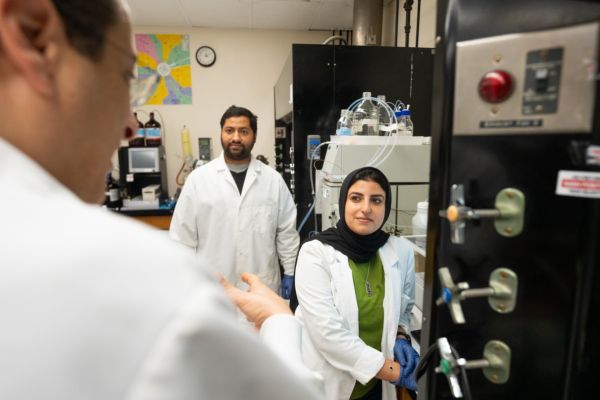 a professor talks to two graduate students in his lab