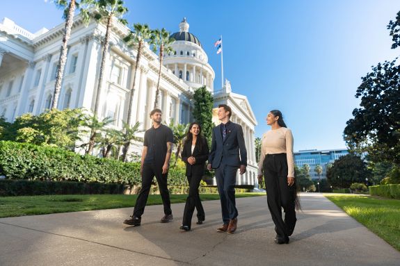 A group of 4 students walk together in front of the CA Capitol Building