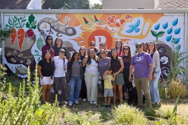 A group of about 15 people pose for a photo in a garden