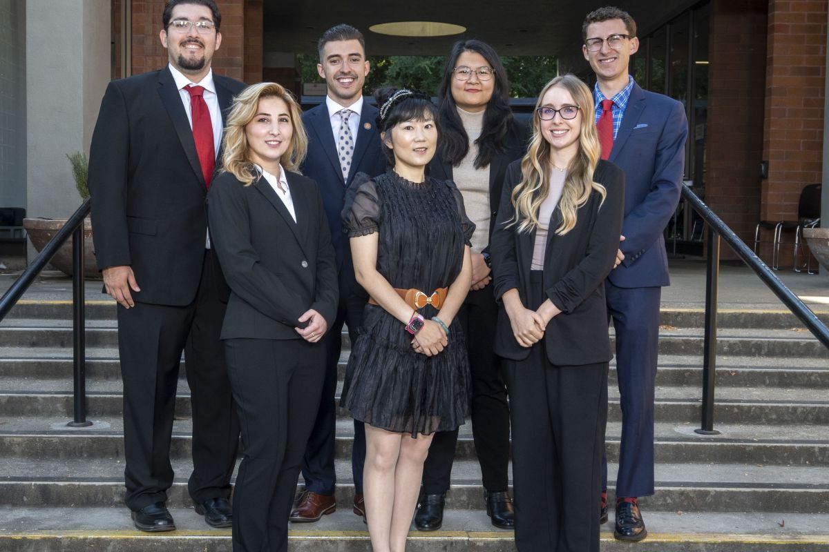 A group of about 8 students pose on the steps of a staircase outdoors