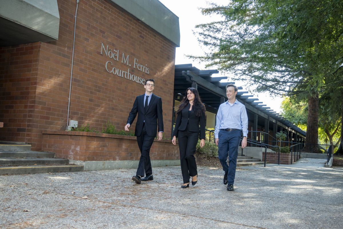 Three individuals walk on campus together