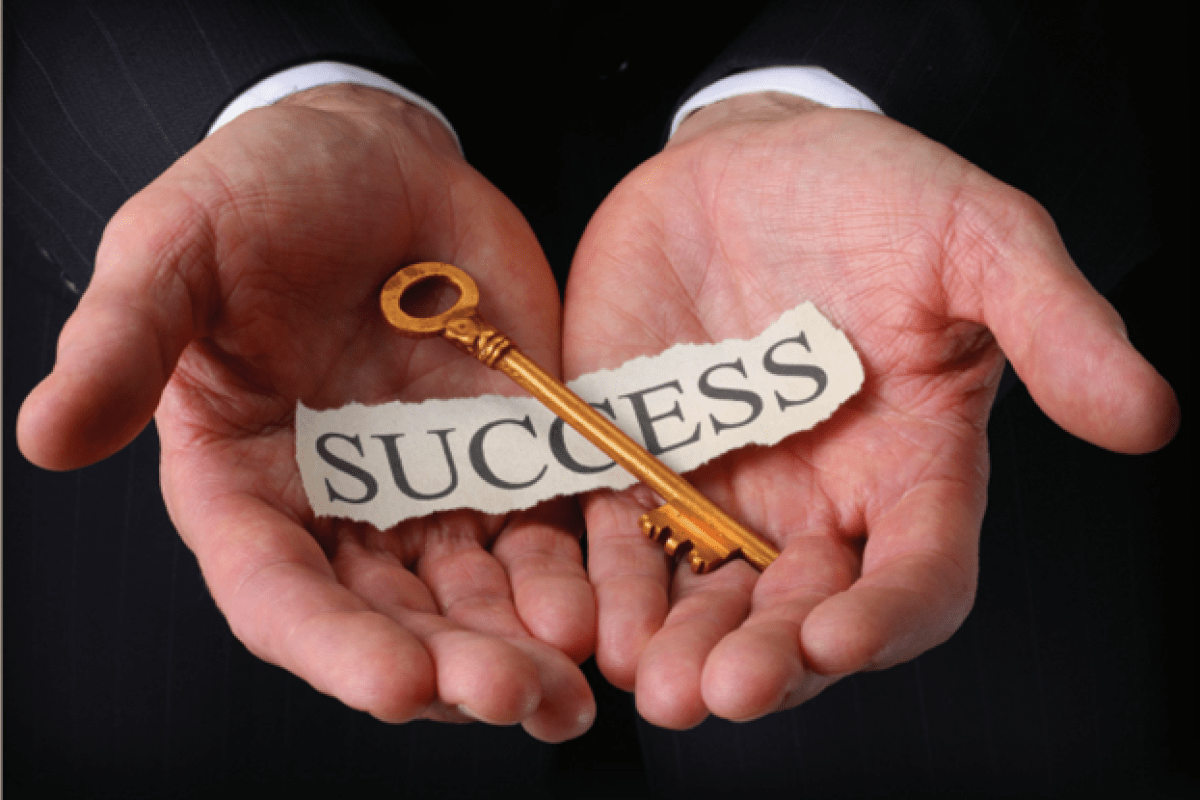 A pair of hands holding a key with the word "success" written on a sheet of paper. 
