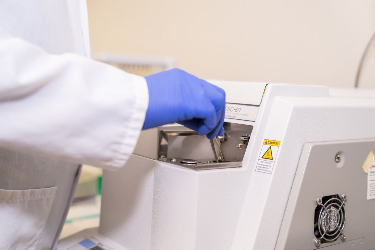 a gloved hand puts a test tube into a centrifuge