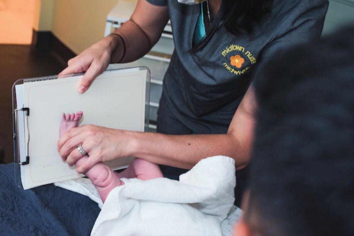 A midwife is making a footprint image of a newborn child.