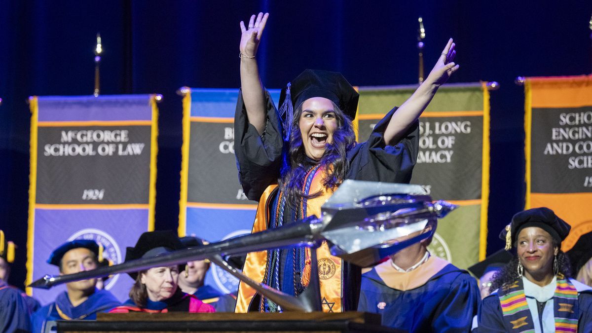 A student cheers as she walks across the stage at commencement.