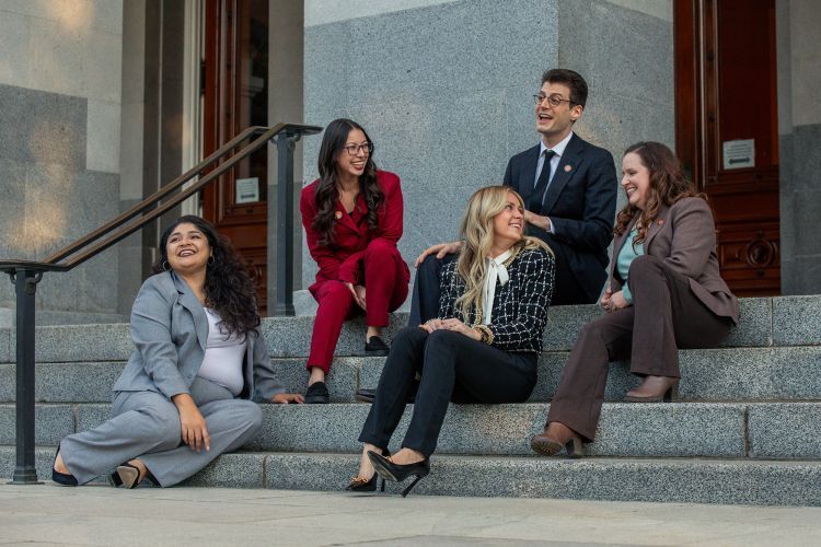 Five students sit on the steps of a government building 