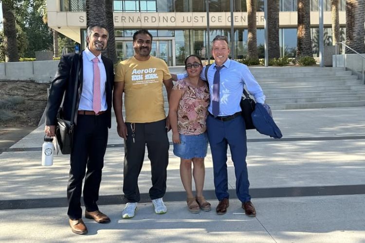 Four people posed in outdoor setting smiling at the camera. 