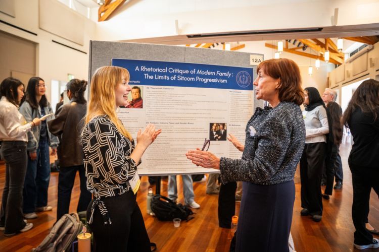 a student presents research in front of a poster