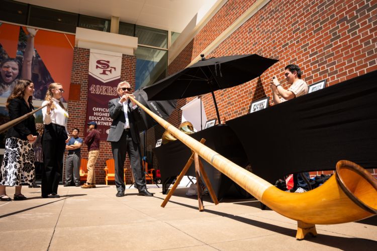 a person plays the alphorn, a 12-foot long wooden musical instrument