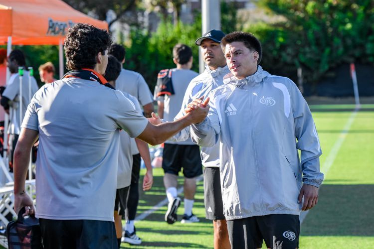 Two men shake hands on a soccer field