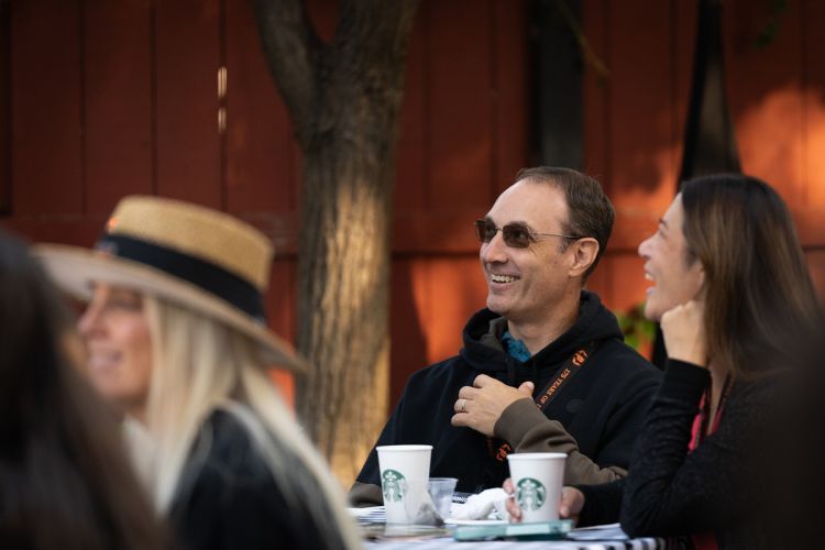 A parent in sunglasses and a black jacket smiles at Homecoming and Family Weekend