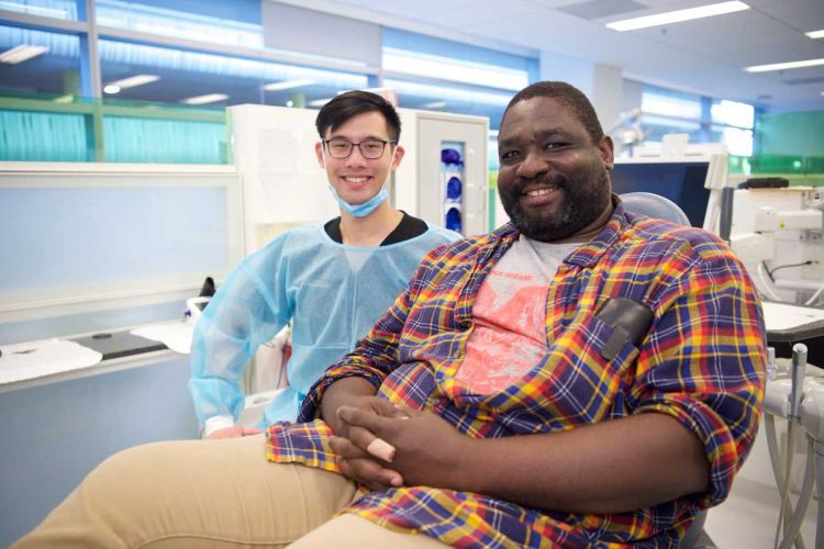 veteran in chair with volunteer at dental clinic