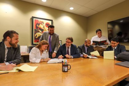 Seven individuals in an indoor setting smiling and looking at books