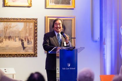 A portrait of a man speaking at a podium