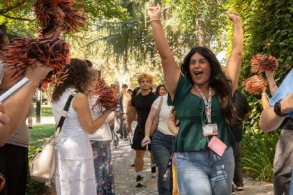 A student cheers in a green shirt surrounded by confetti.