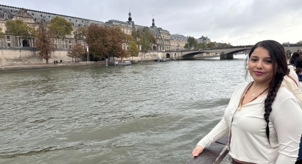 A student stands in front of the Seine River in Paris