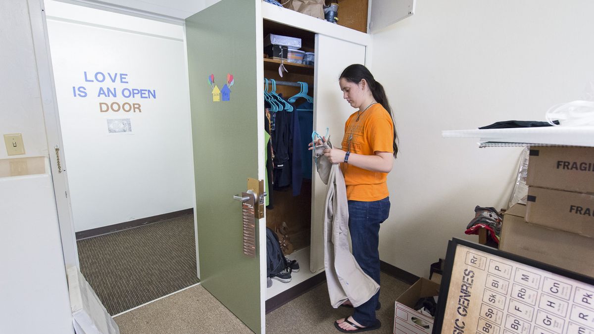student putting clothes in closet