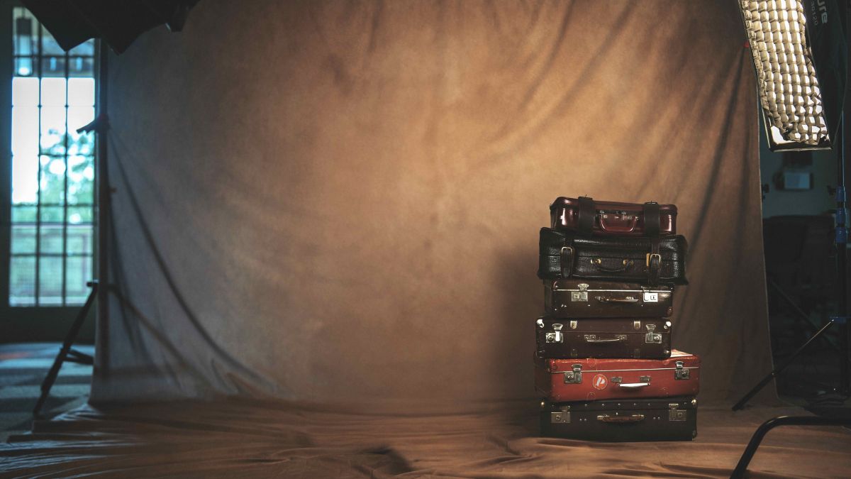 a stack of suitcases sits in front of a brown-colored backdrop