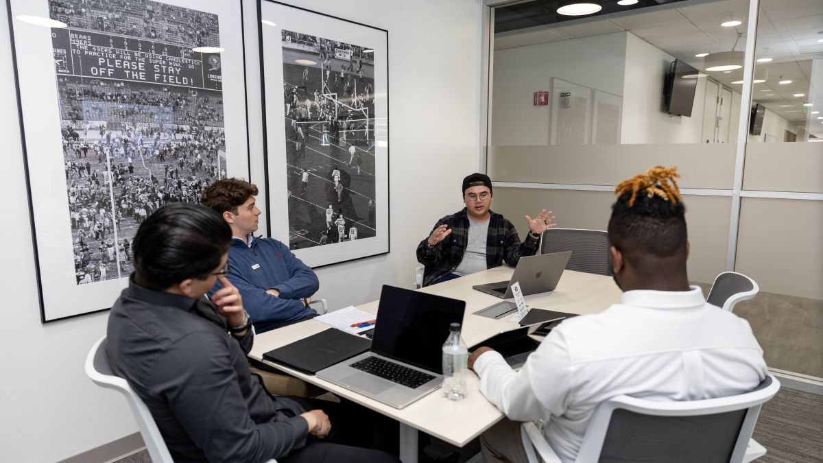 Three Pacific students sit in a 49ers conference room with a staff member